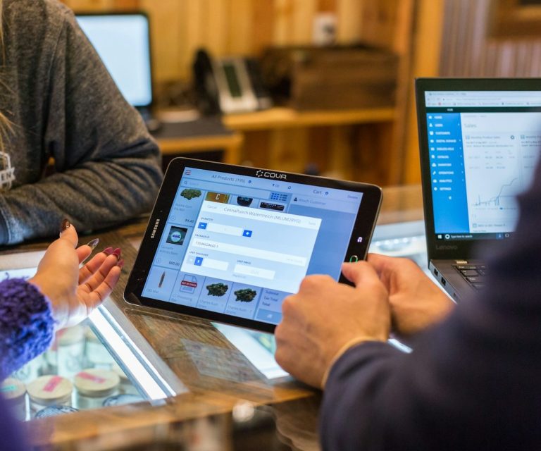 IT-Support Personen verwenden Tablets und Laptops zur Datenbearbeitung in einem Holzinterieur.